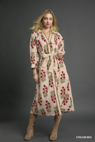 Woman wearing a floral dress with a belt against a gray background
