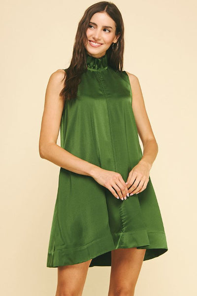 Woman wearing a green dress against a beige background